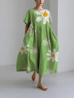 Woman wearing a loose-fitting, white midi dress with short sleeves, featuring bold red-orange floral prints accented with blue centers, paired with flat sandals.