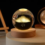 Glowing crystal ball night light with a cloud-like design inside, sitting on a round wooden base on a tabletop in a dimly lit room.