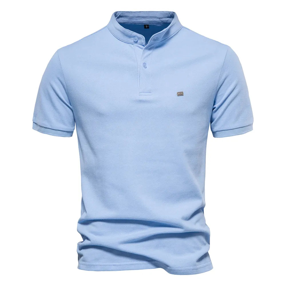 A beige short-sleeved polo shirt with a mandarin collar and a two-button placket. The fabric appears soft, and there is a small embroidered logo on the left chest. The shirt has a modern, slim fit with neatly stitched hems.