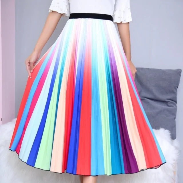 Pleated midi skirt with a gradient design, transitioning from dark black at the waistband to a soft blush pink at the hem, hanging on a black clothing rack next to a vintage-style camera.