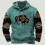 Teal hooded sweatshirt with a kangaroo pocket, featuring a black buffalo graphic with geometric tribal-style patterns and multicolour patterned sleeves.
