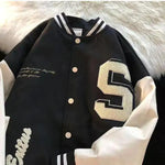 Black varsity jacket with cream sleeves, striped collar and large “S” patch.
