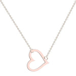 A delicate gold chain necklace featuring a tilted, hollow heart-shaped pendant. The heart is asymmetrically attached at both top curves to the chain, giving it a stylish slant. The background is plain white, highlighting the necklace's elegant and minimalist design.