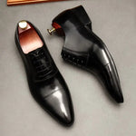 A pair of elegant burgundy leather loafers with a glossy finish. The shoes feature gold-toned metal horsebit detailing across the uppers and are displayed with wooden shoe trees inserted. They have a sleek, elongated silhouette with subtle stitching along the toe cap. The loafers are placed on a dark surface, partially framed by a wooden picture frame, emphasizing their classic and sophisticated style.
