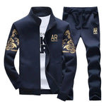 Image of a navy blue tracksuit featuring a zip-up jacket with gold designs on the sleeves and matching pants with a similar design. The jacket is paired with a white t-shirt with bold lettering underneath.
