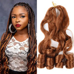Side-by-side image showing a woman with long ombré box braids that transition from dark roots to warm copper-brown ends, and a matching bundle of loose, wavy copper-brown hair extensions with curled tips on a white background.