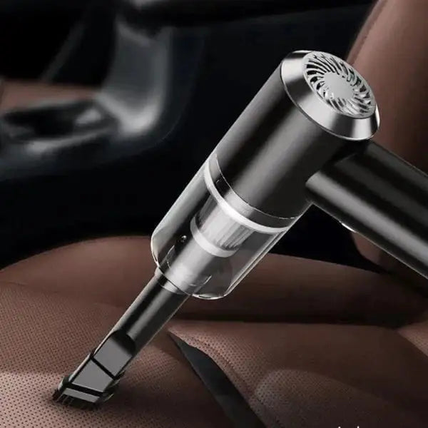 Close-up of a small handheld vacuum with a crevice tool cleaning crumbs from a brown leather car seat.