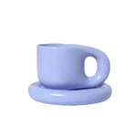 Light lavender ceramic cup with a rounded handle, resting on a matching saucer against a white background.