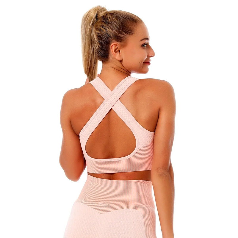 Woman wearing a seamless, textured long-sleeve athletic zip-up top in a light pink and peach gradient, featuring a high collar and thumb holes.