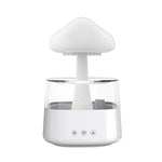 Cloud-shaped rain humidifier/aroma diffuser with a wood-grain base and clear water tank, shown dripping “rain” into the reservoir beside an RGB remote control.