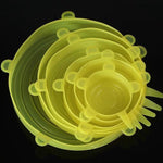 Set of translucent yellow-green silicone stretch lids in multiple sizes, stacked together on a black background, each with small pull tabs around the edge.