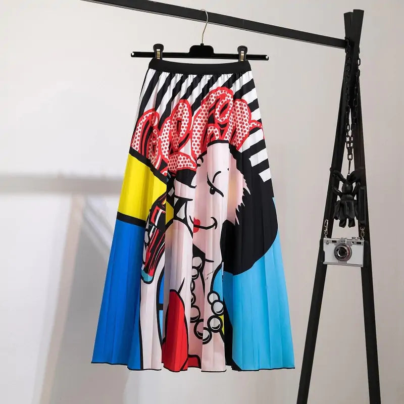 Pleated midi skirt with a gradient design, transitioning from dark black at the waistband to a soft blush pink at the hem, hanging on a black clothing rack next to a vintage-style camera.