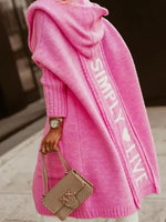 Person wearing a pink hoodie with 'SIMPLY LIVE' text, holding a beige handbag.