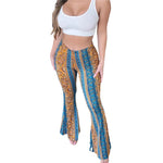 Woman wearing a black crop top and high-waisted, flared bohemian print pants with a mix of geometric and floral patterns in shades of purple, white, and maroon, posing with one hand on her hip
