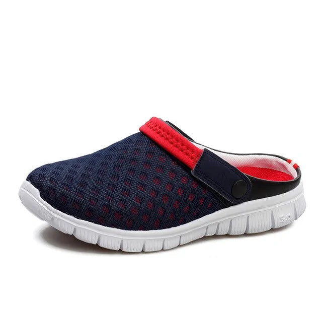 A navy blue slip-on clog sneaker with a breathable perforated mesh upper, open-back design, and an adjustable heel strap in black and bright red. It features a lightweight white flexible sole and a casual sporty look.