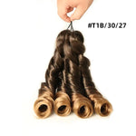 Hand holding four spiral-curled hair extension bundles on a white background, with an ombré color blend from dark brown roots to lighter brown and honey-blonde ends, labeled “#T1B/30/27.”