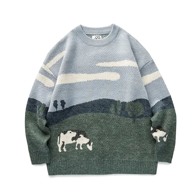Light blue crewneck knit sweater with a pastoral landscape design—white clouds in the sky above green hills and trees, with small white cows near the hem and on the right sleeve.
