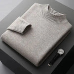 A neatly folded beige knitted sweater with a ribbed high collar and cuffs, placed on a dark grey surface. Beside the sweater, a classic wristwatch with a black leather strap and a silver dial is positioned, adding a touch of elegance to the composition.