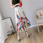 Pleated midi skirt with a gradient design, transitioning from dark black at the waistband to a soft blush pink at the hem, hanging on a black clothing rack next to a vintage-style camera.