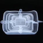 Set of clear rectangular silicone stretch lids in multiple sizes, stacked on a black background, with small pull tabs on the sides.