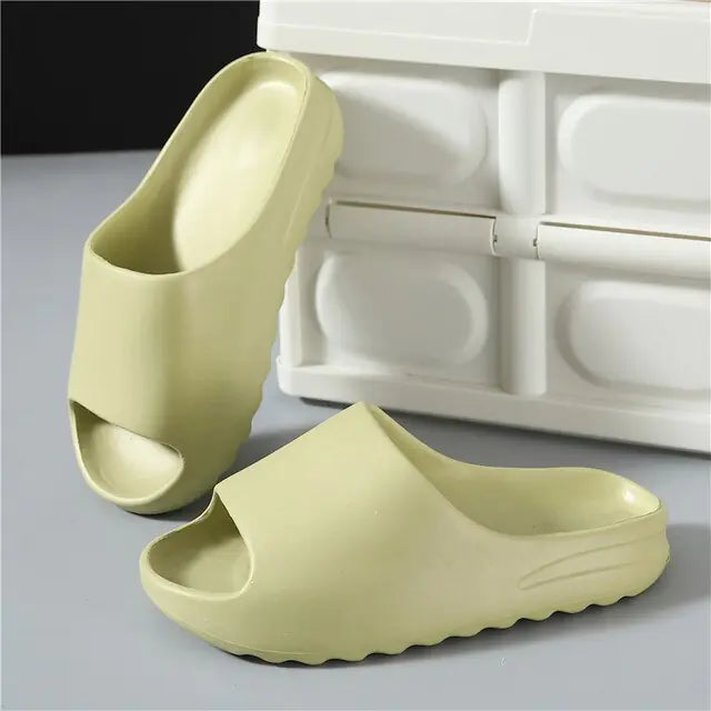 A pair of futuristic white and red open-toe slide sandals with a sleek, curved design and large side cutouts, displayed on a minimalist gray and white background. An inset image shows a beige version of the sandals worn with black socks.