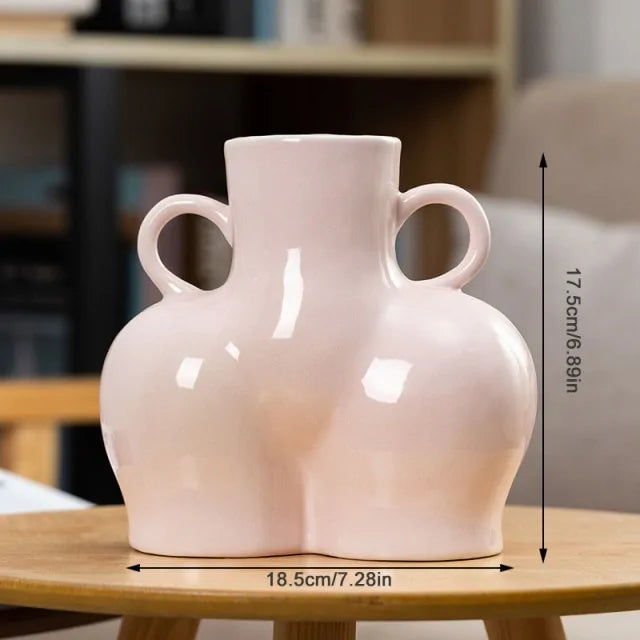 Glossy light pink abstract body vase with side handles, 17.5 cm height and 18.5 cm width.
