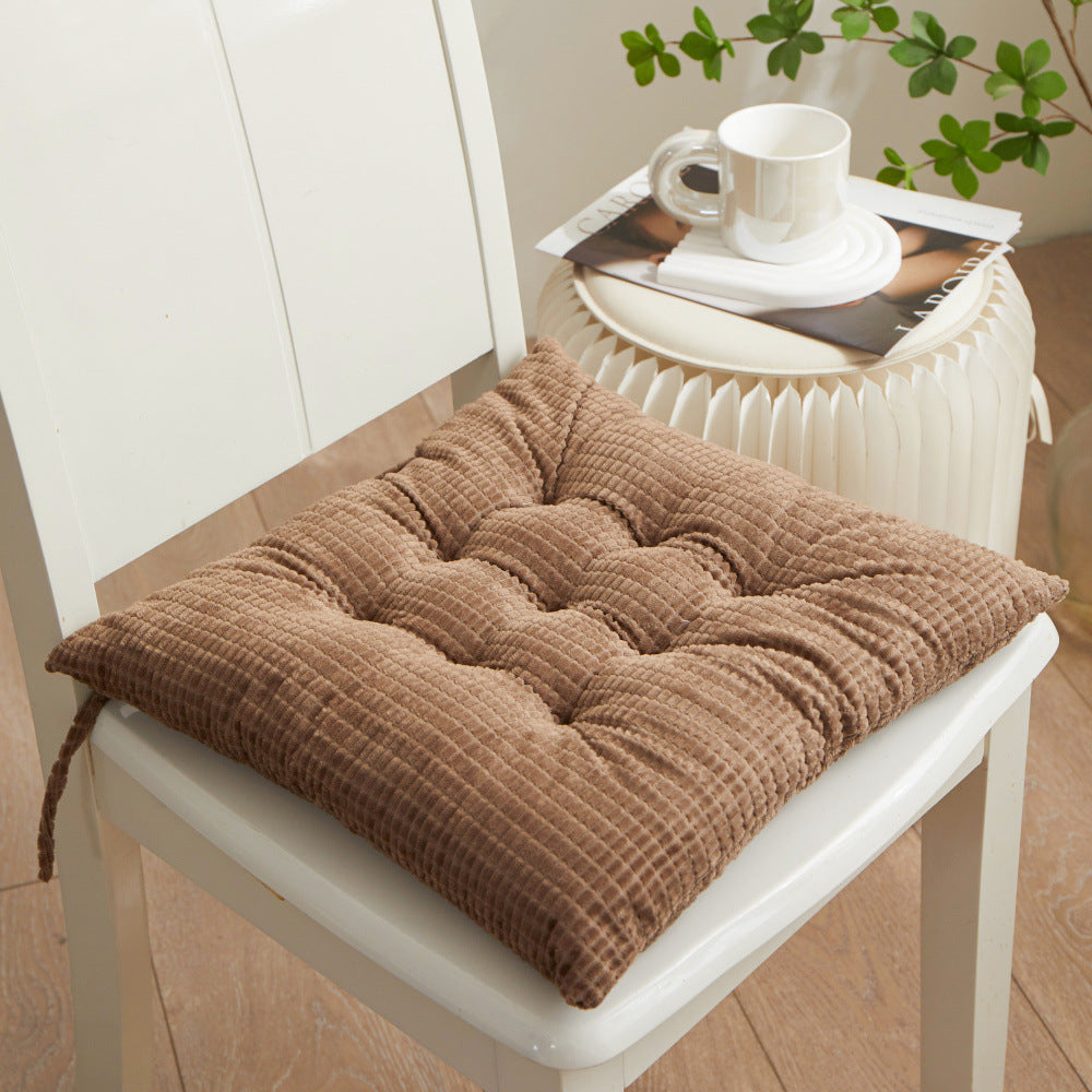Brown textured cushion on a white chair with a table in the background