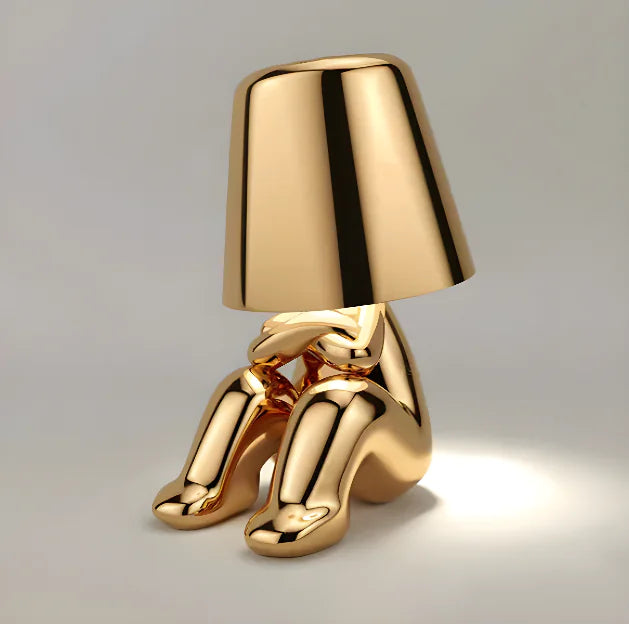Gold seated figure table lamp with lampshade.
