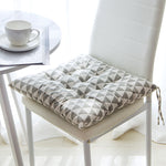 Gray geometric patterned chair cushion on a white chair with a cup and saucer in the background.