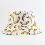 White bucket hat with an all-over yellow banana print outlined in black, shown on a light background.