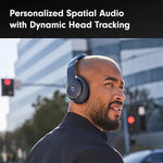 Man wearing dark over-ear Beats headphones outdoors in a city setting, with text reading “Personalized Spatial Audio with Dynamic Head Tracking.”