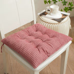 Pink cushion on a white chair with a small table in the background