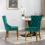 Two teal velvet chairs with gold accents in a dining room setting.