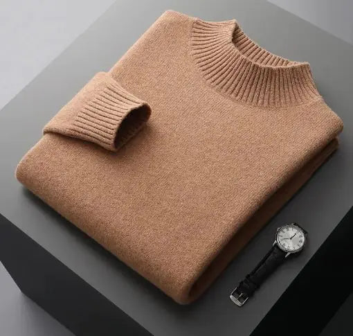 A neatly folded beige knitted sweater with a ribbed high collar and cuffs, placed on a dark grey surface. Beside the sweater, a classic wristwatch with a black leather strap and a silver dial is positioned, adding a touch of elegance to the composition.