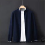 A navy blue zip-up cardigan with a subtle ribbed texture, layered over a plain white T-shirt, displayed on a wooden hanger against a dark background. The cardigan has a minimalist design with a soft and warm fabric, making it a stylish and versatile choice for cool weather.