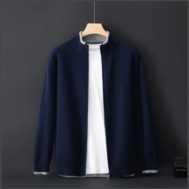 A navy blue zip-up cardigan with a subtle ribbed texture, layered over a plain white T-shirt, displayed on a wooden hanger against a dark background. The cardigan has a minimalist design with a soft and warm fabric, making it a stylish and versatile choice for cool weather.