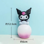 Small Kuromi-style figurine sitting on a round white-to-pink gradient base, shown with measurement markings indicating about 12.5 cm tall and 6 cm wide.