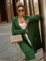 Woman wearing a green cardigan over a white top, holding a beige handbag.