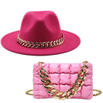 Bright pink wide-brim hat with a gold chain band, paired with a quilted pink handbag featuring a chunky gold chain strap.