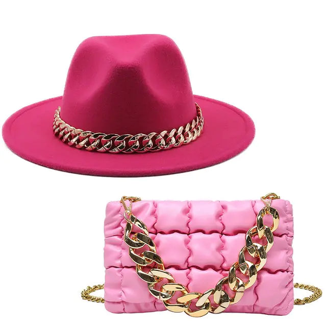 Bright pink wide-brim hat with a gold chain band, paired with a quilted pink handbag featuring a chunky gold chain strap.