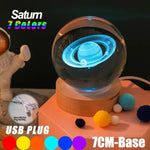 Glowing crystal ball night light with a 3D Saturn design inside, sitting on a wooden base, with text advertising “Saturn 7 Colors,” “USB PLUG,” and a “7CM-Base.