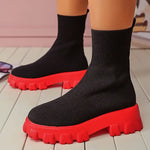 A pair of chunky lavender sock boots with thick platform soles and ribbed knit uppers, displayed on a gray tiled floor against a light-colored wall.