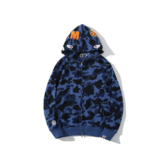 Blue and black camouflage zip-up hoodie with shark-face hood graphics, ribbed cuffs and hem, and bold orange letter detail on the hood.