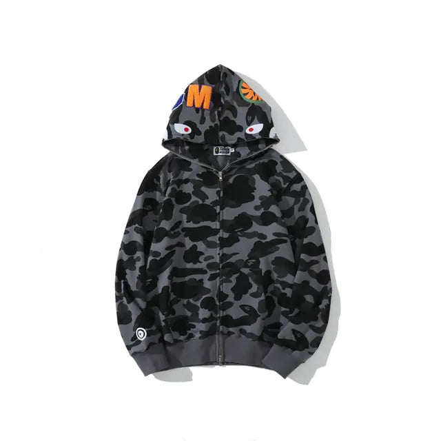 Blue and black camouflage zip-up hoodie with shark-face hood graphics, ribbed cuffs and hem, and bold orange letter detail on the hood.