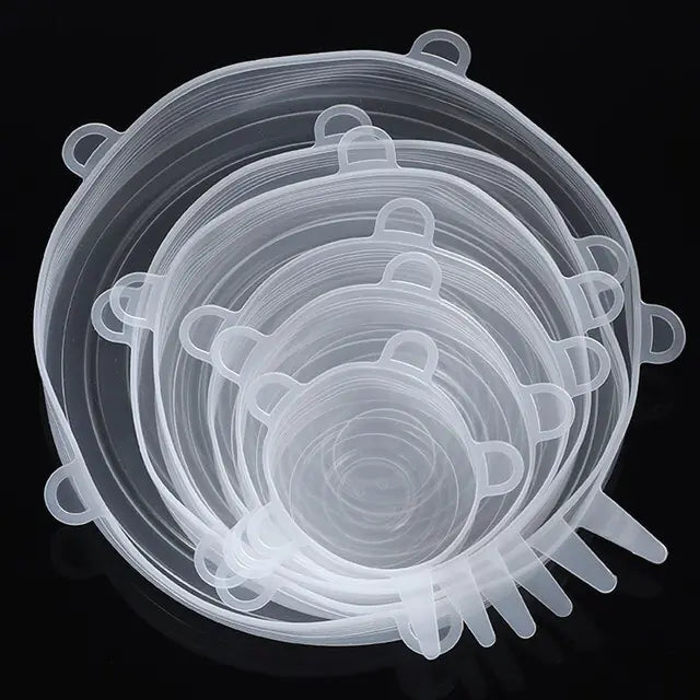 Set of clear silicone stretch lids in multiple sizes, stacked together on a dark background, with pull tabs visible around the edges.