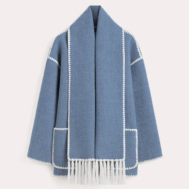 Dark wool coat with white blanket stitch trim, featuring front buttons, large patch pockets, and an attached matching scarf with fringe detailing draped over the shoulder. The coat is displayed against a plain white background.