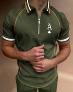 Man wearing an olive-green short-sleeve polo with a half-zip collar, white and black stripe trim, contrast piping, and a white “A” with spade logo on the chest.