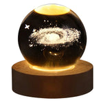 Glowing crystal ball night light with a 3D galaxy and star design inside, sitting on a round wooden LED base against a white background.