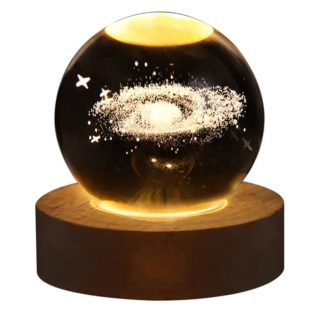 Glowing crystal ball night light with a 3D galaxy and star design inside, sitting on a round wooden LED base against a white background.