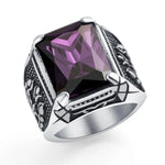 A men's ring with an intricate silver band and a large, dark red rectangular gemstone in the center.